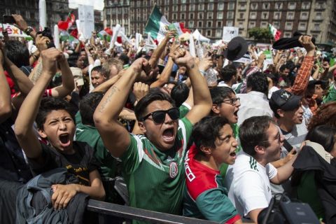 Fans celebrate Mexico's win during the Mexico vs. Germany World Cup soccer match, as they watched it on an outdoor screen in Mexico City's Zocalo, Sunday, June 17, 2018. Mexico won it's first match against Germany 1-0. (AP Photo/Anthony Vazquez)