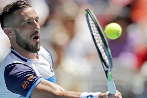 Damir Dzumhur of Bosnia and Herzegovina makes a forehand return to Switzerland's Stan Wawrinka during their first round singles match at the Australian Open tennis championship in Melbourne, Australia, Tuesday, Jan. 21, 2020. (AP Photo/Andy Wong)