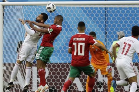 Iran's Roozbeh Cheshmi, left, and Morocco's Ayoub El Kaabi, right, fight for the ball, during the group B match between Morocco and Iran at the 2018 soccer World Cup in the St. Petersburg Stadium in St. Petersburg, Russia, Friday, June 15, 2018. (AP Photo/Andrew Medichini)