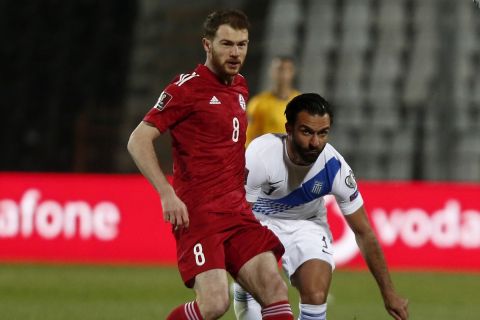 Greece's Giorgos Tzavellas, right, and Georgia's Budu Zivzivadze go for the ball during the World Cup 2022 group B qualifying soccer match between Greece and Georgia at Toumba stadium in Thessaloniki, northern Greece, Wednesday, March 31, 2021. (AP Photo/Giannis Papanikos)