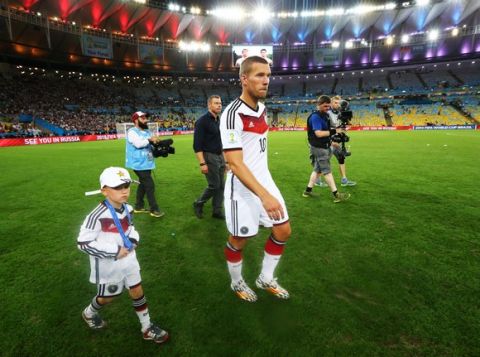 RIO DE JANEIRO, BRAZIL - JULY 13: Lukas Podolski of Germany walks on the field with his son Louis Podolski after defeating Argentina 1-0 in extra time during the 2014 FIFA World Cup Brazil Final match between Germany and Argentina at Maracana on July 13, 2014 in Rio de Janeiro, Brazil.  (Photo by Martin Rose/Getty Images)