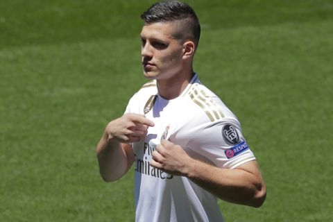 Serbia forward Luka Jovic points to the club emblem on his shirt during his official presentation after signing for Real Madrid at the Santiago Bernabeu stadium in Madrid, Spain, Wednesday, June 12, 2019. The 21-year-old Jovic, who scored 17 goals in 32 Bundesliga games for Eintracht Frankfurt last season, agreed to a six-year deal with Madrid. (AP Photo/Manu Fernandez)