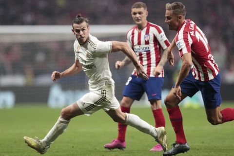 Real Madrid's Gareth Bale, left, and Atletico Madrid's Marcos Llorente, right, vie for the ball during the Spanish La Liga soccer match between Atletico Madrid and Real Madrid at the Wanda Metropolitano stadium in Madrid, Saturday, Sept. 28, 2019. (AP Photo/Bernat Armangue)