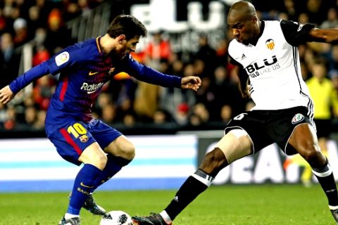 FC Barcelona's Lionel Messi, left, duels for the ball with Valencia's Geoffrey Kondogbia, right, during the Spanish Copa del Rey, semifinal, second leg, soccer match between FC Barcelona and Valencia at the Mestalla stadium in Valencia, Spain, Thursday Feb. 8, 2018. (AP Photo/Alberto Saiz)
