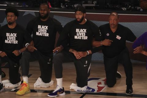 Los Angeles Lakers' LeBron James, second from left, wears a Black Lives Matter shirt and kneels with teammates during the national anthem prior to an NBA basketball game against the Los Angeles Clippers, Thursday, July 30, 2020, in Lake Buena Vista, Fla. (Mike Ehrmann/Pool Photo via AP)