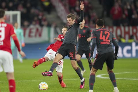 CORRECTS DATE -- Mainz's Dominik Kohr, left, and Bayern's Thomas Mueller, center, fight for the ball during a German Cup round of 16 Soccer match between FSV Mainz 05 and Bayern Munich, in Mainz, Germany, Wednesday, Feb. 1, 2023. (AP Photo/Michael Probst)