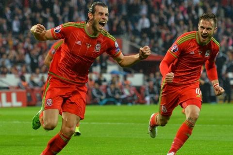 Wales's midfielder Gareth Bale (L) celebrates scoring the opening goal with Wales's midfielder Aaron Ramsey (R) during the Euro 2016 qualifying group B football match between Wales and Belgium at Cardiff City Stadium in Cardiff, south Wales, on June 12, 2015.  AFP PHOTO / GLYN KIRK        (Photo credit should read GLYN KIRK/AFP/Getty Images)