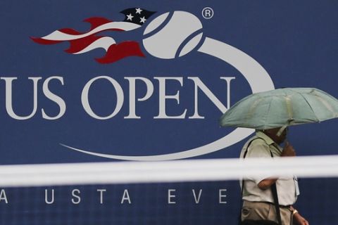 A person passes a logo for the US Open before play is to resume at the 2012 US Open tennis tournament,  Saturday, Sept. 8, 2012, in New York. (AP Photo/Charles Krupa)