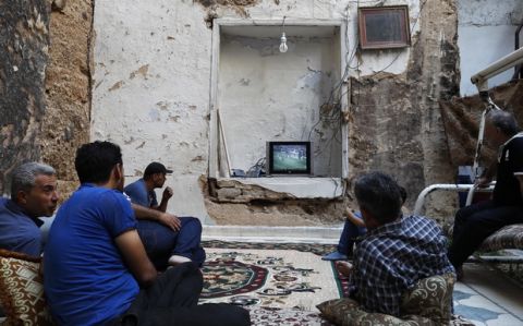 Syrians watch the World Cup soccer final match between France and Croatia at their home, that was partially destroyed by the war leaving two of its rooms without a ceiling, in the town of Ain Terma, in the Eastern Ghouta suburb of Damascus, Syria, Sunday, July 15, 2018. (AP Photo/Hassan Ammar)