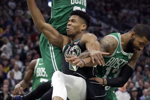 Milwaukee Bucks' Giannis Antetokounmpo, center, is fouled as he attempts to shoot against Boston Celtics' Marcus Morris, top, and Marcus Smart (13) during the first half of an NBA basketball game Thursday, Feb. 21, 2019, in Milwaukee. (AP Photo/Aaron Gash)
