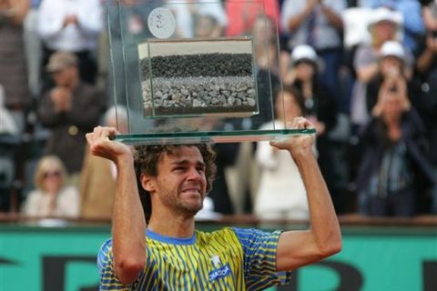 Three time French Open winner Gustovo Kuerten, of Brazil, shows a trophy for his contribution tennis after being defeated by France's Paul-Henri Mathieu during their first round match of the French Open tennis tournament, Sunday May 25, 2008 at the Roland Garros stadium in Paris. Kuerten bids farewell to tennis at the site of his biggest triumphs. (AP Photo/David Vincent)