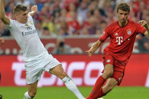 Munich's Thomas Mueller, right, challenges for the ball with Madrid's Toni Kroos during the friendly soccer match between FC Bayern and Real Madrid in the Allianz Arena stadium in Munich, southern Germany, Wednesday, Aug. 5, 2015. (AP Photo/Kerstin Joensson)