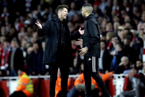 Atletico coach Diego Simeone, left, talks to an assistant referee during the Europa League semifinal first leg soccer match between Arsenal FC and Atletico Madrid at the Arsenal stadium in London, Britain, Thursday, April 26, 2018. (AP Photo/Tim Ireland)