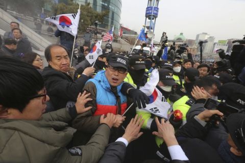 South Korean protesters struggle with police officers as police use fire extinguishers during a rally against a visit of North Korean Hyon Song Wol, head of a North Korean art troupe, in front of Seoul Railway Station in Seoul, South Korea, Monday, Jan. 22, 2018. Dozens of conservative activists have attempted to burn a large photo of North Korean leader Kim Jong Un as the head of the North's hugely popular girl band passed by them at a Seoul railway station. (AP Photo/Ahn Young-joon)