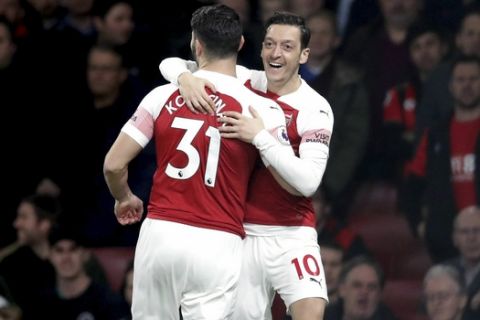 Arsenal's Mesut Ozil, right, celebrates scoring his side's first goal of the game against Bournemouth, with teammate Sead Kolasinac, centre, during their English Premier League soccer match at the Emirates Stadium in London, Wednesday Feb. 27, 2019. (Adam Davy/PA via AP)