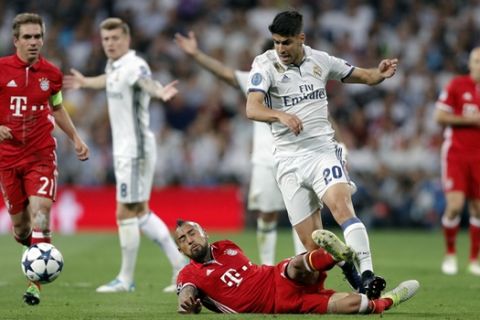 Bayern's Arturo Vidal, on the ground, fouls Real Madrid's Marco Asensio during the Champions League quarterfinal second leg soccer match between Real Madrid and Bayern Munich at Santiago Bernabeu stadium in Madrid, Spain, Tuesday April 18, 2017. Vidal was shown a second yellow card for the foul. (AP Photo/Daniel Ochoa de Olza)