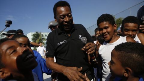 DISTRIBUTED FOR HUBLOT - Soccer star Pele cheers children as he attends the inauguration of a soccer pitch at the entrance of Jacarezinho shantytown in Rio de Janeiro, Brazil on Friday, June 27, 2014. As part of the international #HublotLovesFootball campaign and to highlight Hublot's presence as both the "Official Timekeeper" and the "Official Watch" of Brazil 2014 FIFA World Cup, Ricardo Guadalupe, CEO of Hublot, joins Pele and local children to officially open the football pitch that Hublot built in the heart of the Jacarezinho favela in Rio de Janeiro on Friday, June 27, 2014. Hublot's aim is support the local community and directly benefit Brazilians, particularly those living in Rio de Janeiro, where the brand has set up its Hublot Palace HQ for the duration of the FIFA World Cup. (Dado Galdieri/AP Images for Hublot)