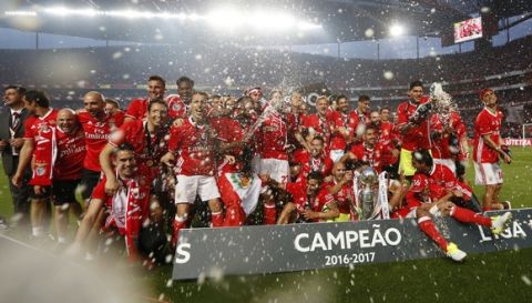 Benfica players celebrate with sparkling wine and the Portuguese league trophy at the end of the soccer match between Benfica and Vitoria de Guimaraes at the Luz stadium in Lisbon, Saturday, May 13, 2017. Benfica won the match 5-0 to clinch the championship title with one round left to play. (AP Photo/Pedro Rocha)