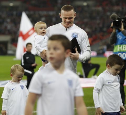 England's Wayne Rooney, center rear, and his children walk off the pitch after Rooney was given a commemorative plaque prior to the international friendly soccer match between England and the United States, Rooney's 120th cap, at Wembley stadium, Thursday, Nov. 15, 2018. (AP Photo/Alastair Grant)