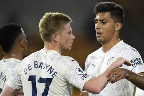 Manchester City's Kevin De Bruyne, centre, is congratulated by teammate Rodrigo, right after scoring his team's first goal during the English Premier League soccer match between Wolverhampton Wanderers and Manchester City at Molineux Stadium in Wolverhampton, England, Monday, Sept. 21, 2020. (Stu Forster/Pool via AP)