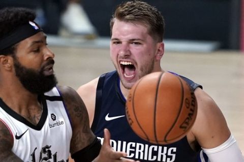 Dallas Mavericks' Luka Doncic, right, reacts after making a basket as Los Angeles Clippers' Marcus Morris Sr. (31) reaches for the ball during the second half of an NBA basketball first round playoff game Sunday, Aug. 23, 2020, in Lake Buena Vista, Fla. (AP Photo/Ashley Landis, Pool)