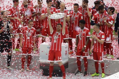Bayern's Xabi Alonso lifts the trophy as his team celebrate winning the Bundesliga title after the German first division Bundesliga soccer match between FC Bayern Munich and SC Freiburg at the Allianz Arena stadium in Munich, Germany, Saturday, May 20, 2017. (AP Photo/Matthias Schrader)
 
