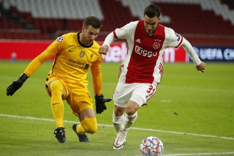 Ajax's Nicolas Tagliafico, right, tries to score against Liverpool's goalkeeper Adrian, during the group D Champions League soccer match between Ajax and Liverpool at the Johan Cruyff ArenA in Amsterdam, Netherlands, Wednesday, Oct. 21, 2020. (AP Photo/Peter Dejong)