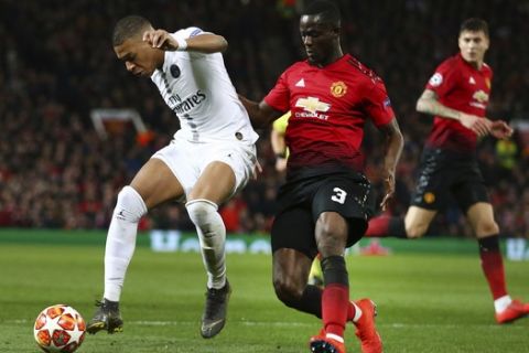 Paris Saint Germain's Kylian Mbappe, left, defends the ball as Manchester United's Eric Bailly goes to challenge during the Champions League round of 16 soccer match between Manchester United and Paris Saint Germain at Old Trafford stadium in Manchester, England, Tuesday, Feb. 12,2019.(AP Photo/Dave Thompson)