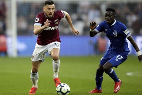 West Ham's Robert Snodgrass runs with the ball away from Everton's Idrissa Gueye, right, during the English Premier League soccer match between West Ham United and Everton at London Stadium in London, Saturday, March 30, 2019. (AP Photo/Tim Ireland)