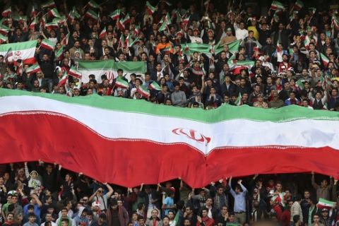 Iranian soccer fans cheer while holding an Iranian huge flag prior to start of a match of their country and Oman for the FIFA 2018 World Cup and AFC 2019 Asian Cup joint qualifiers, at Azadi Stadium in Tehran, Iran, Tuesday, March 29, 2016. Iran won the game 2-0. (AP Photo/Vahid Salemi)