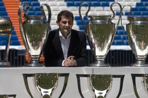 Goalkeeper Iker Casillas poses by some of the trophies he won as a player with Real Madrid after a press conference at the Santiago Bernabeu stadium in Madrid, Spain, Monday July 13, 2015. Casillas appeared with the clubs president a day after he gave an emotional press conference alone putting an end to his 25 years as a Real Madrid goalkeeper. Casillas will now play for FC. Porto. (AP Photo/Paul White)