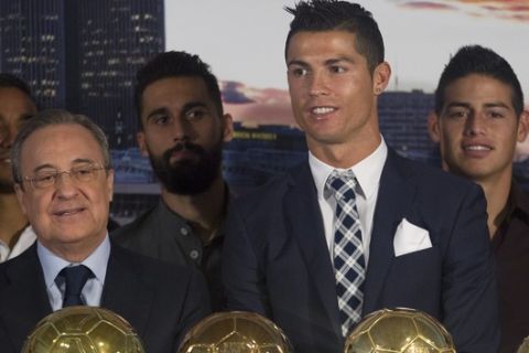 Real Madrids striker Cristiano Ronaldo, center, poses with club President Florentino Perez, left and team members after being given a silver boot award for scoring the most goals for the club during a ceremony at the Santiago Bernabeu stadium in Madrid, Spain, Friday Oct. 2, 2015. Real Madrid paid tribute to Ronaldo, who recently overtook Raul Gonzalez to become the club's all-time highest goalscorer with a tally of 324 goals. (AP Photo/Paul White)