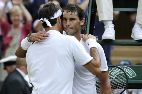 Switzerland's Roger Federer hugs Spain's Rafael Nadal after defeating him in a men's singles semifinal match on day eleven of the Wimbledon Tennis Championships in London, Friday, July 12, 2019. (AP Photo/Ben Curtis)