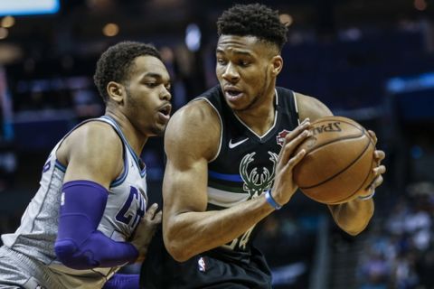 Milwaukee Bucks forward Giannis Antetokounmpo, right, looks to drive against Charlotte Hornets forward P.J. Washington in the first half of an NBA basketball game in Charlotte, N.C., Sunday, March 1, 2020. (AP Photo/Nell Redmond)