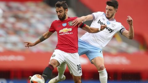 Manchester United's Bruno Fernandes, left, vie for the ball with West Ham's Declan Rice during the English Premier League soccer match between Manchester United and West Ham at the Old Trafford stadium in Manchester, England, Wednesday, July 22, 2020. (Cath Ivill/Pool via AP)