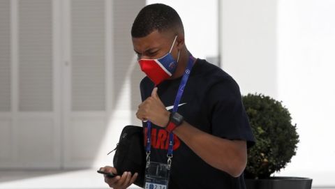 PSG's Kylian Mbappe gestures to fans as he leaves the team hotel for a training session in Lisbon, Friday Aug. 21, 2020. PSG will play Bayern in the Champions League final on Sunday. (AP Photo/Armando Franca)