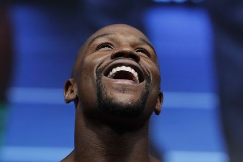 Floyd Mayweather Jr. laughs on the scale during a weigh-in Friday, Aug. 25, 2017, in Las Vegas. Mayweather is scheduled to fight Conor McGregor in a boxing bout Saturday. (AP Photo/John Locher)