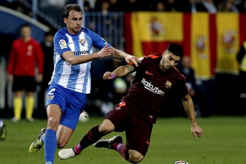Malaga's Ignasi Miquel fights for the ball against Barcelona's Luis Suarez, right, during a Spanish La Liga soccer match between Malaga and Barcelona in Malaga, Spain, Saturday, March 10, 2018. (AP Photo/M.Pozo)