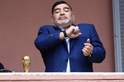Former soccer great Diego Maradona acknowledges fans next to a small, generic replica of a FIFA World Cup soccer trophy at the Casa Rosada government house after his meeting with Argentine President Alberto Fernandez in Buenos Aires, Argentina, Thursday, Dec. 26, 2019. Decades ago, Maradona held up his team's real trophy at this spot on the balcony after winning the World Cup in Mexico in 1986.  (AP Photo/Marcos Brindicci)