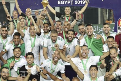 Algeria's captain Riyad Mahrez, center, holds up the trophy at the end of the African Cup of Nations final soccer match between Algeria and Senegal in Cairo International stadium in Cairo, Egypt, Friday, July 19, 2019. Algeria won 1-0. (AP Photo/Hassan Ammar)