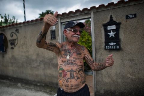 TO GO WITH AFP STORY by Javier Tovar
Brazilian football club Botafogo fan Delneri Martins Viana, a 69-year-old retired soldier, gestures at neighbours outside his house in Rio de Janeiro, Brazil, on January 18, 2014. Delneri has 83 tattoos on his body dedicated to Botafogo and describes himself as the club's biggest fan.   AFP PHOTO / YASUYOSHI CHIBA