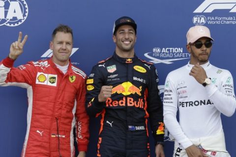 Pole position winner Red Bull driver Daniel Ricciardo of Australia, center, celebrates flanked by third placed Ferrari driver Sebastian Vettel of Germany, left, and second placed Mercedes driver Lewis Hamilton of Britain at the end of the qualifying session for Sunday's Monaco Formula One Grand Prix at the Monaco racetrack, in Monaco, Saturday, May 26, 2018. (AP Photo/Claude Paris)