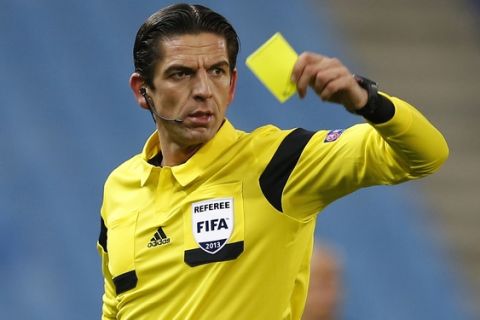 FIFA referee Deniz Aytekin of Germany holds up a yellow card during a Group G Champions League soccer match between Atletico Madrid and FC Porto at the Vicente Calderon stadium in Madrid, Wednesday Dec. 11, 2013. (AP Photo/Paul White)