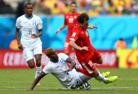 MANAUS, BRAZIL - JUNE 25: Admir Mehmedi of Switzerland is tackled by Brayan Beckeles of Honduras during the 2014 FIFA World Cup Brazil Group E match between Honduras and Switzerland at Arena Amazonia on June 25, 2014 in Manaus, Brazil.  (Photo by Clive Mason - FIFA/FIFA via Getty Images)