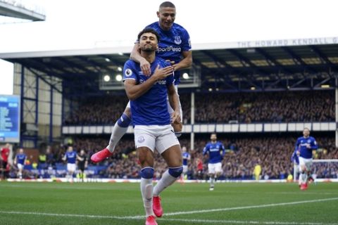 Everton's Dominic Calvert-Lewin celebrates with teammate Everton's Richarlison, top, after scoring the opening goal during the English Premier League soccer match between Everton and Manchester United at Goodison Park in Liverpool, England, Sunday, March 1, 2020. (AP Photo/Jon Super)