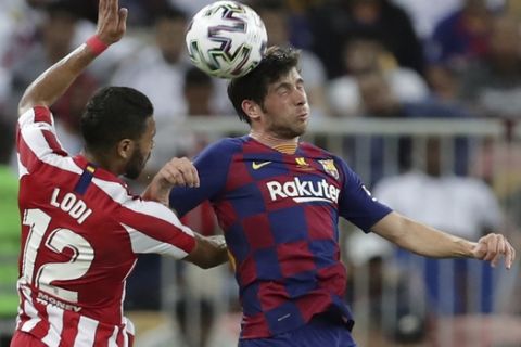Atletico Madrid's Renan Lodi, left, jumps for the ball with Barcelona's Sergi Roberto during the Spanish Super Cup semifinal soccer match between Barcelona and Atletico Madrid at King Abdullah stadium in Jiddah, Saudi Arabia, Thursday, Jan. 9, 2020. (AP Photo/Hassan Ammar)
