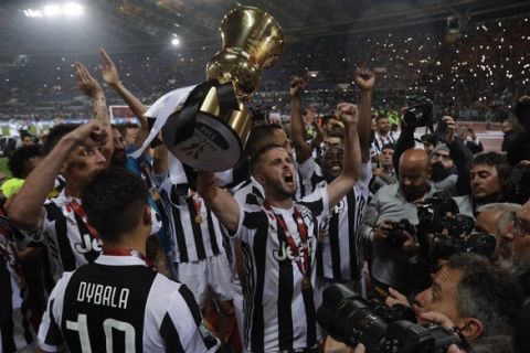 Juventus' Miralem Pjanic holds up the trophy as he celebrates with teammates after beating AC Milan 4-0 in the Italian Cup final soccer match, at the Rome Olympic stadium, Wednesday, May 9, 2018. (AP Photo/Gregorio Borgia)