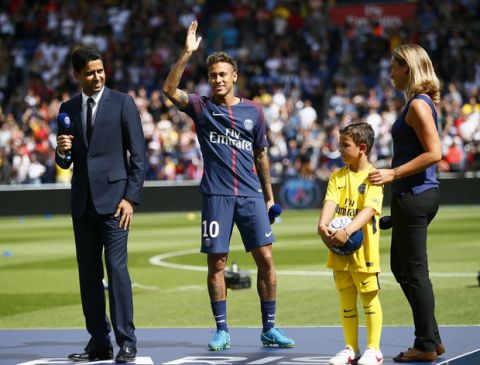 Brazilian soccer star Neymar waves to fans as he stands next to PSG president Nasser Ghanim Al-Khelaïfi at the Parc des Princes stadium in Paris, Saturday, Aug. 5, 2017, during his official presentation to fans ahead of Paris Saint-Germain's season opening match against Amiens. Neymar would not play in the club's season opener as the French football league did not receive the player's international transfer certificate before Friday's night deadline. The Brazil star became the most expensive player in soccer history after completing his blockbuster transfer from Barcelona for 222 million euros ($262 million) on Thursday. (AP Photo/Francois Mori)
