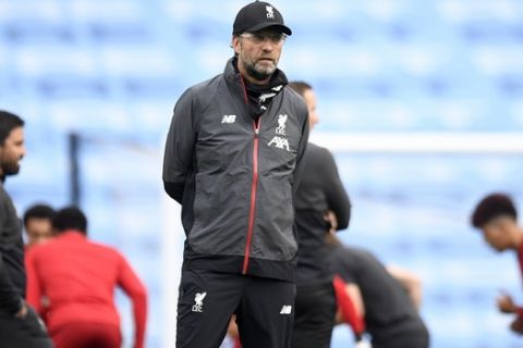 Liverpool's manager Jurgen Klopp watches as his players warm up ahead of the English Premier League soccer match between Manchester City and Liverpool at Etihad Stadium in Manchester, England, Thursday, July 2, 2020. (AP Photo/Peter Powell,Pool)