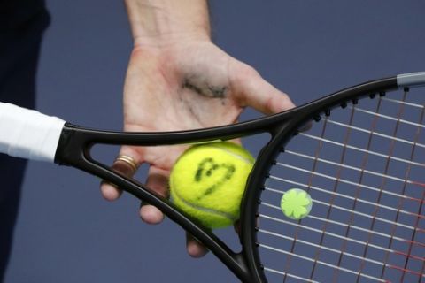 The tennis ball of french veteran Nicolas Mahut is marked with a sign during a training session in the French Tennis Federation center near the grounds of the French Open in Paris, Wednesday, May 13, 2020 under the watchful eye of a team doctor and courtside trainers. Professional tennis players resumed training in France after the end of lockdown amid the coronavirus pandemic. (AP Photo/Francois Mori)